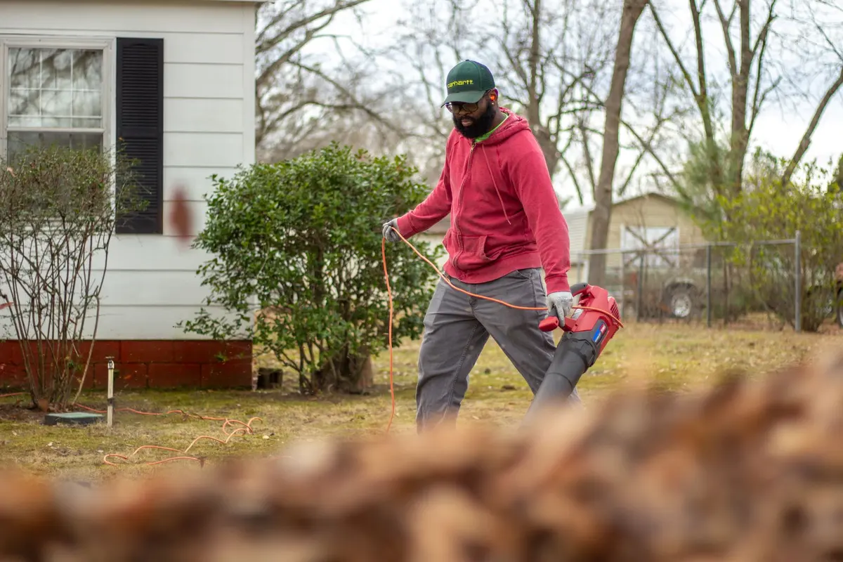 Yard cleanup in Bakersfield, CA: worker blowing leaves off a front yard